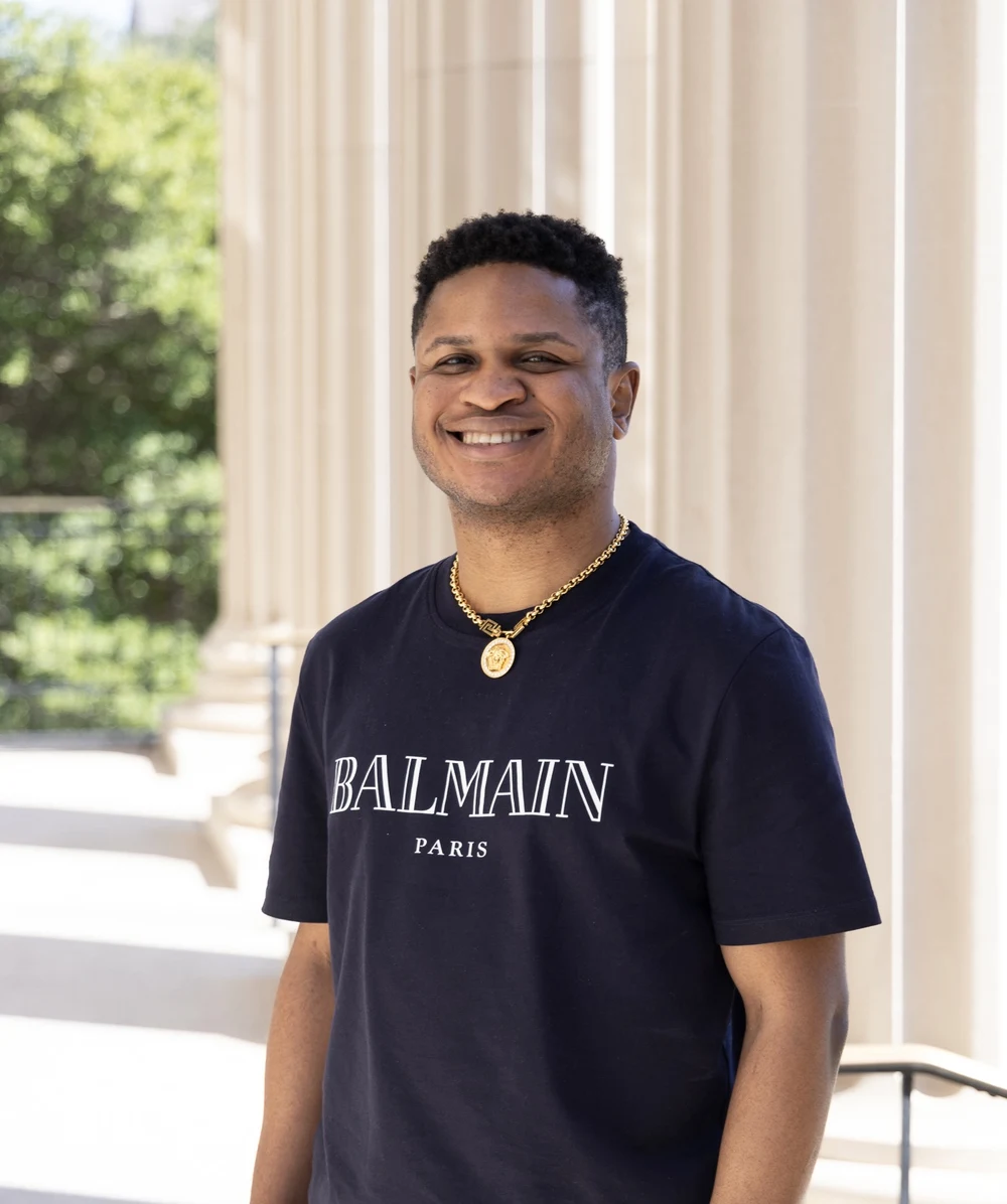 Jerry Falade standing beside a row of columns